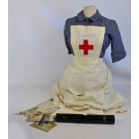 A WWI period nurse/midwife uniform, a cotton sling printed with the uses to which it could be put,