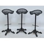 A set of three cast iron bar stools with tractor type seats,