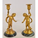 A pair of early 20th century decorative gilt metal cherubic candlesticks raised on stepped green