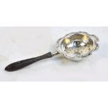 A George V hallmarked silver circular tea strainer with shaped rim and turned ebonised handle,