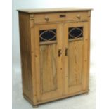 A European pine cupboard with upper drawer flanked by carved detail,