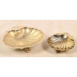 A George V hallmarked silver scallop shaped butter dish raised on three ball feet with clear