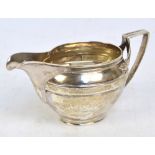 A George III hallmarked silver cream jug of plain oval form with angled leaf decorated handle,