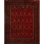 A carpet decorated with geometrical motifs within an ornamental border on red ground, 237 x 168cm.
