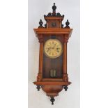 A small Vienna style eight day wall clock with shaped pediment and turned finials above the