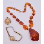 An amber coloured bead necklace, a yellow metal oval locket pendant,