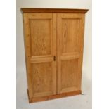 A pine wardrobe with pair of panelled doors enclosing four shelves, on plinth base, height 191cm,