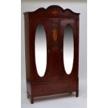 An early 29th century mahogany wardrobe with shaped inlaid pediment above two hinged doors set with
