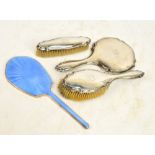 A George V hallmarked silver backed three piece dressing table set comprising a shaped circular