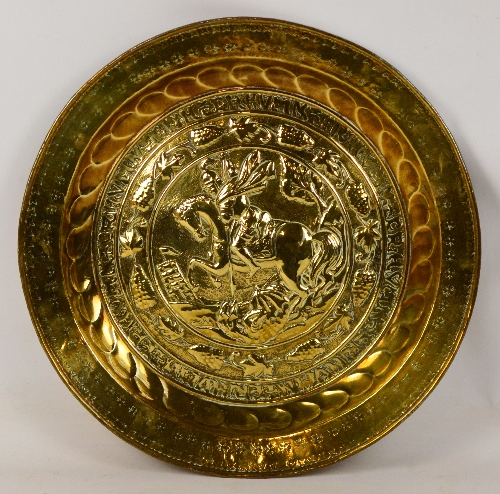 A 19th century brass alms dish with embossed decoration within a grape and vine border and floral