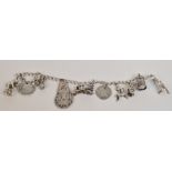 A white metal link bracelet suspending a number of silver and white metal charms including a