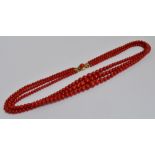 A three strand graduated coral bead necklace with 14ct yellow gold clasp.