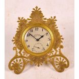 A late 19th/early 20th century brass cased easel backed eight day timepiece with engraved pierced