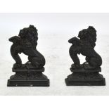 A pair of cast iron door stops modelled as seated lions on plinth bases, height 38cm.
