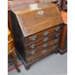 An early to mid 19th century oak bureau with elaborate brass escutcheon,