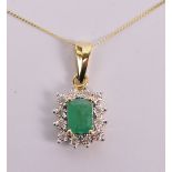 A 9ct yellow gold fine link chain supporting a 9ct emerald and diamond pendant,