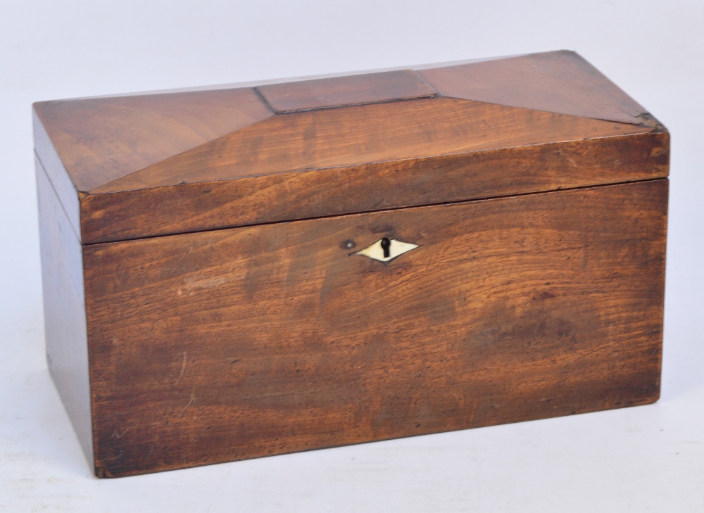 An early Victorian mahogany tea caddy of rectangular form with panelled hinged lid enclosing three