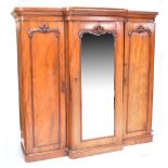 A Victorian mahogany breakfront wardrobe with mirrored central door enclosing three slides and