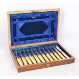 A walnut cased set of twelve electroplated bladed and ivory handled fish knives and forks,