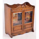 A 1920s oak smoker's cabinet with pair of glazed doors enclosing glass pipe racks and fitted