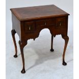 A 1920s walnut feather and crossbanded lowboy with three drawers and shaped apron,