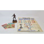 A metal trophy figure of a footballer and football raised on a circular wooden plinth,