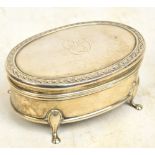 A George V hallmarked silver jewellery box of oval form with ornamental decorated border,