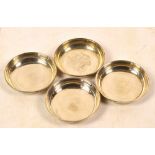 A set of four George V hallmarked silver circular dishes of plain form with cast rims,