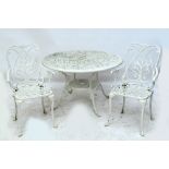 A white painted cast metal circular garden table with pierced scroll decoration with four supports