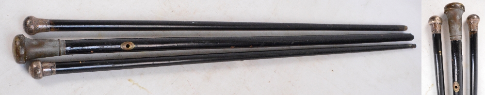 Three ebonised walking canes, one with a hallmarked silver knob for Chester 1920,