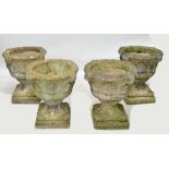 A set of four large composite stone urns decorated with acanthus leaves and scrolling rims,