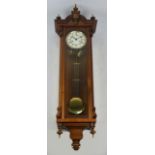 A contemporary walnut cased twin weight Vienna style wall clock with shaped pediment above circular