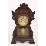 An early 20th century American gingerbread walnut cased eight day clock,