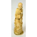 A Japanese Meiji period carved ivory okimono of a gentleman seated upon a log with turtle by his