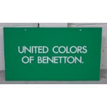 A Benetton advertising sign 'United Colors of Benetton' on a green ground, 40 x 71cm.