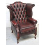 A burgundy leather Chesterfield Queen Anne style wing back chair.