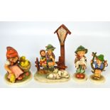 Four Hummel figures to include a young girl feeding chicks, a boy carrying a lamb,