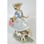 A Lladró figurine of a young girl with a basket of flowers and a puppy at her feet.