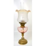 An early 20th century gilt metal oil lamp with clear pink font, height 56cm.