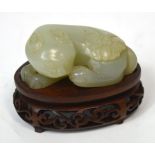 A Chinese carved mutton fat jade figure of a cat with butterfly upon its back on shaped rosewood