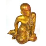 An unusual 19th century Chinese carved wooden gilded and 'jewel' set kneeling boy wearing elaborate