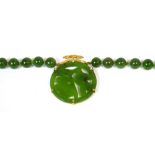 A jade bead necklace suspending a jade pendant in a yellow metal bamboo style mount,