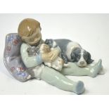 A Lladró figurine of a sleeping young boy holding sleeping puppies with the mother at his feet.