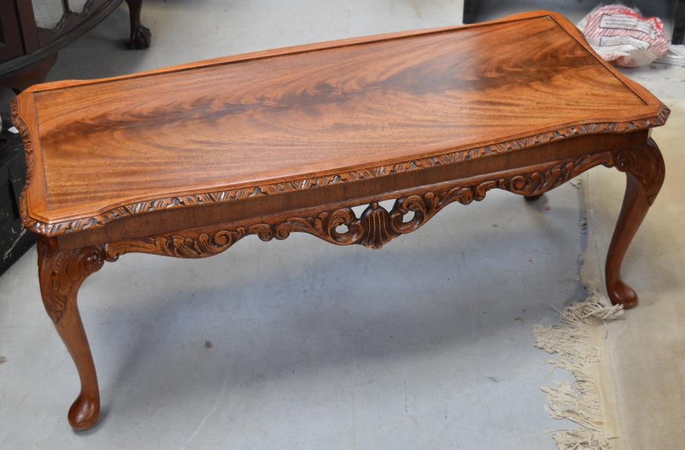 A modern light oak coffee table with carved knees on cabriole legs.