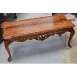 A modern light oak coffee table with carved knees on cabriole legs.