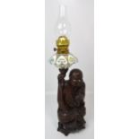 A 20th century carved hardwood or rootwood oil lamp, the support in the form of an Immortal,