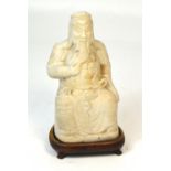 A Chinese carved white marble figure of a seated Immortal modelled stroking his beard with a dragon