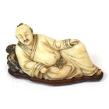 A Chinese carved soapstone figure of a male lying back upon a rock, on shaped rosewood base,