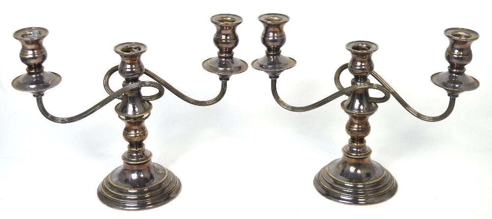 A pair of Elizabeth II loaded hallmarked silver two branch candelabra,