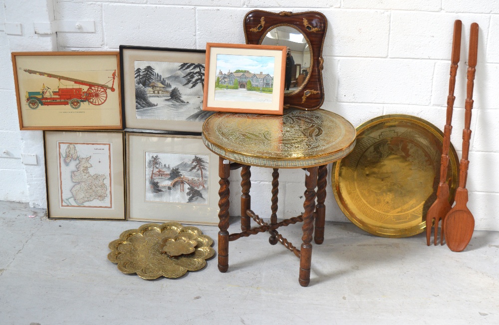 A collapsible wooden brass topped table, a decorative wall mirror, brass trays, prints,